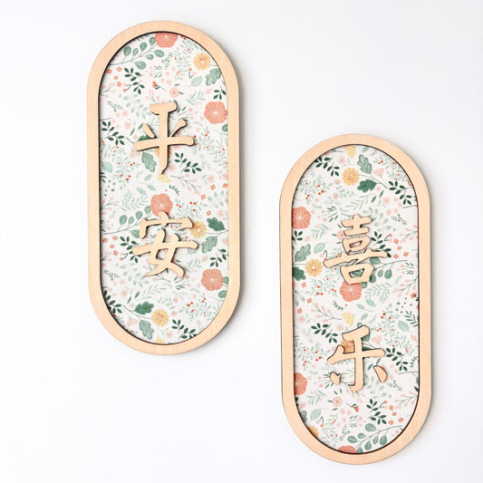 Two oval wooden wall plaques with floral patterns and Chinese characters, displayed on a clean white background.