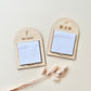 Two personalized wooden name badges with sticky note holders, displayed on a light beige background with dried decorative grass stems. One badge is engraved with 'Mr Izree' and a lightning bolt, and the other with '歕品团' (Teacher Chen) and a small heart.