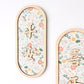 Two vertical oval wooden wall plaques with floral-patterned inserts and raised Chinese characters, shown against a clean white background.