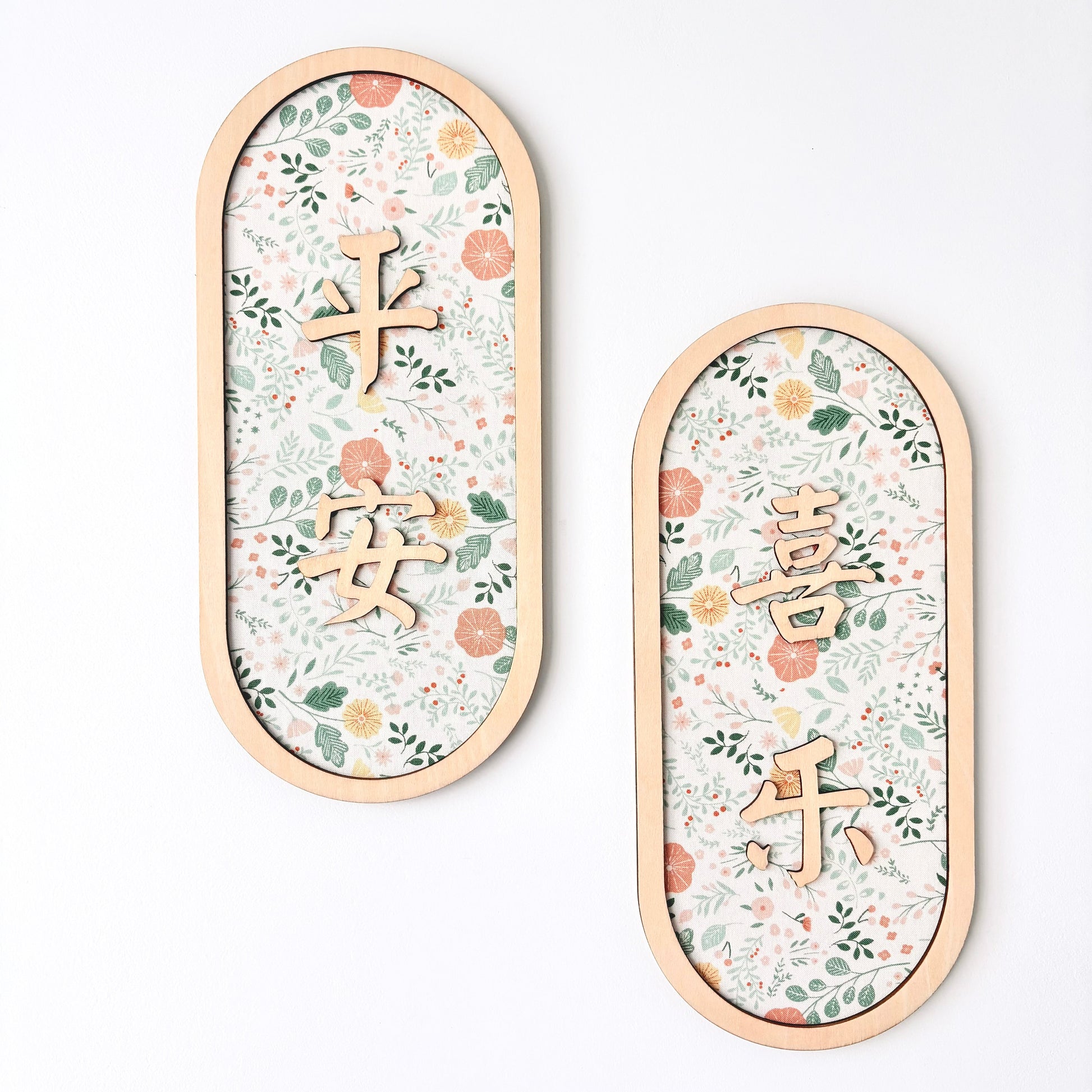 Two oval wooden wall plaques with floral patterns and Chinese characters, displayed on a clean white background.
